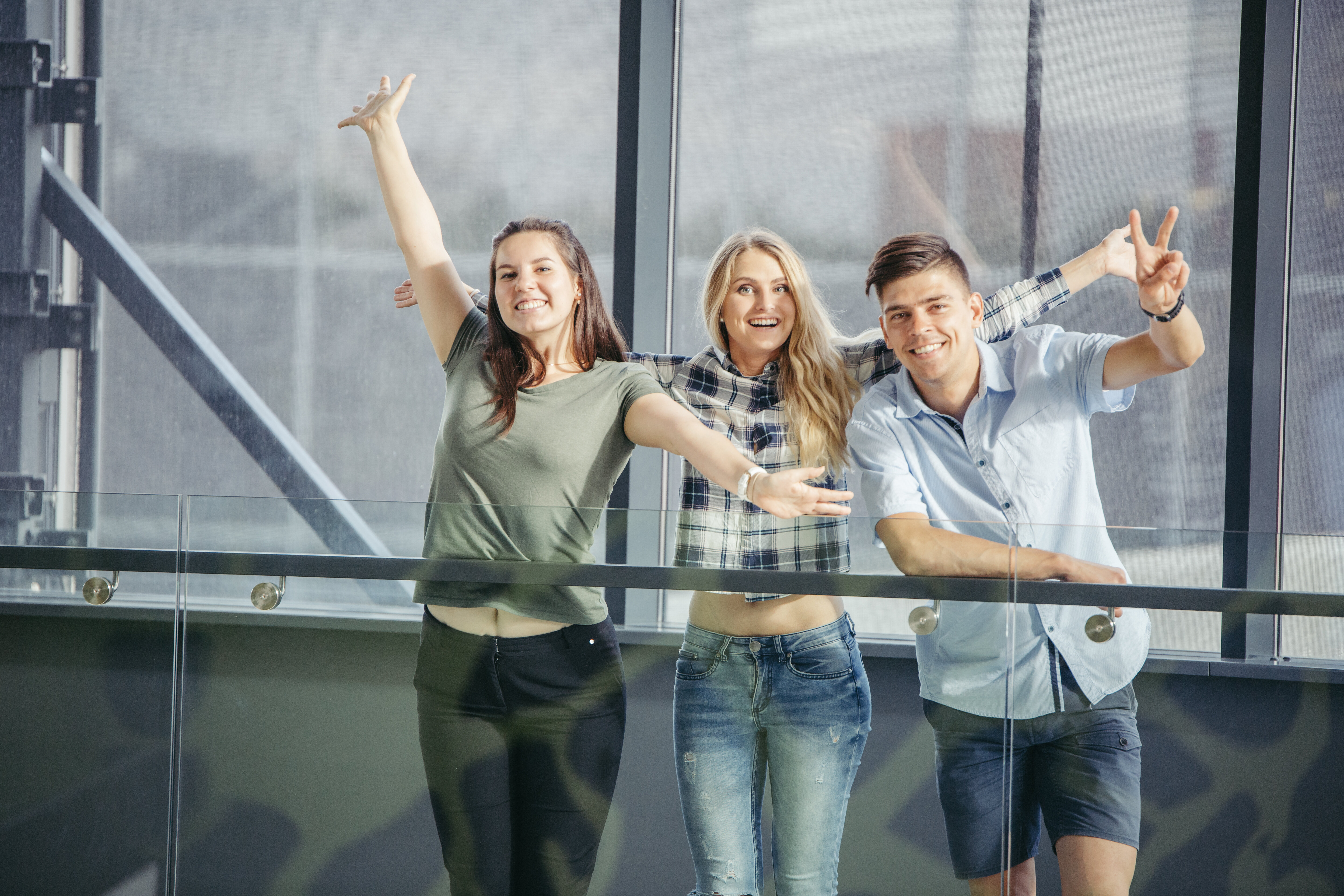 Three young employees stand on a balcony