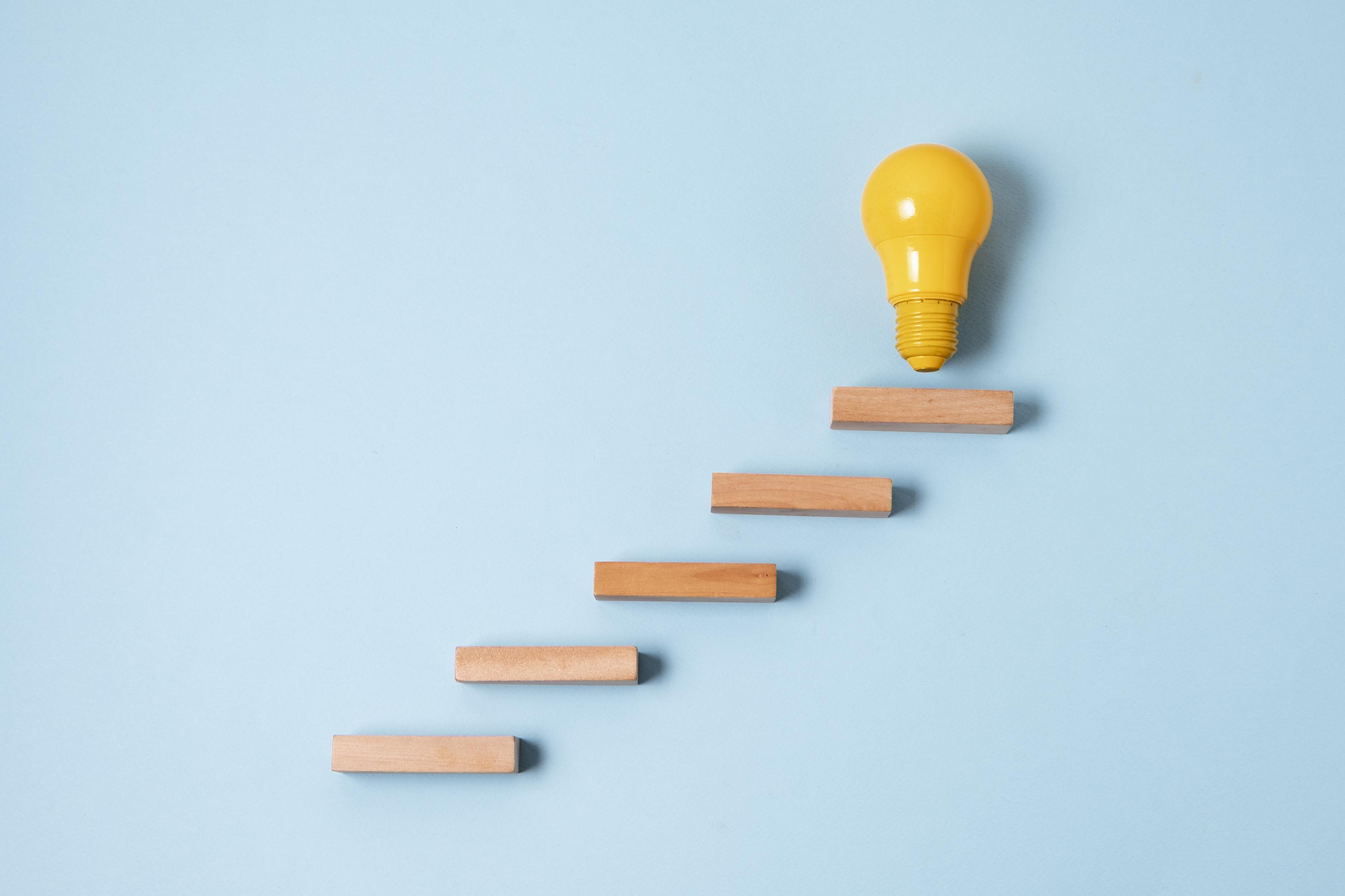 A single yellow light bulb on top of wooden blocks.