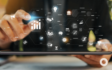 Hands of a person interacting with a tablet displaying a network of interconnected business symbols.