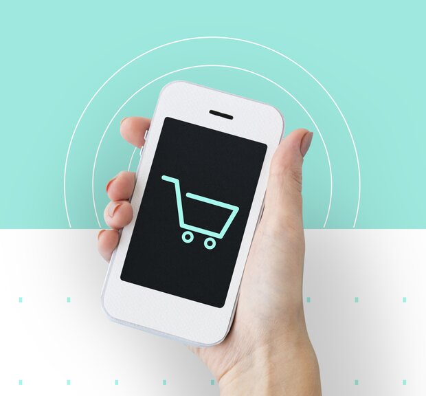 One hand holds a smartphone with a shopping cart icon displayed on the screen, indicating payment by PAYONE.